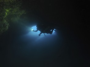 Diver, cave diver with lamp in dark underwater cave explores the surrounding area. Fraskeric dive