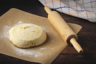 Dough on baking paper with a rolling pin next to it