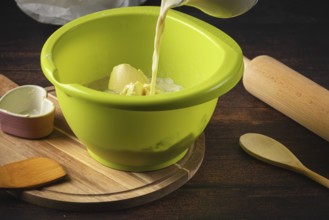 Milk is poured into a green bowl with other baking ingredients