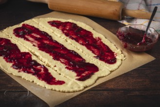 Rolled dough is spread with red marmalade