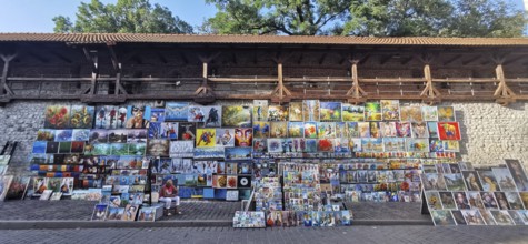 Many colorful paintings hang for sale on a wall, Krakow, Poland