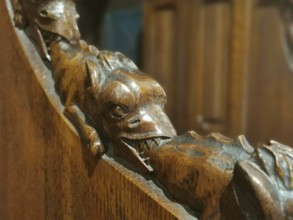 Wood carving of a dragon (draconis) biting the tail of the dragon in front of it in a detailed