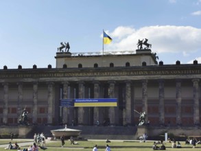 People relax on the lawn in front of the old museum on Museum Island in Berlin where the Ukrainian