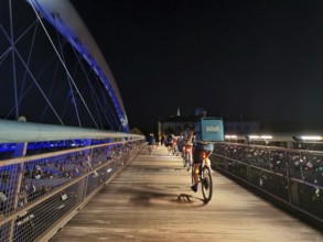 Delivery service Cyclists cross an illuminated bridge with railings on which countless padlocks