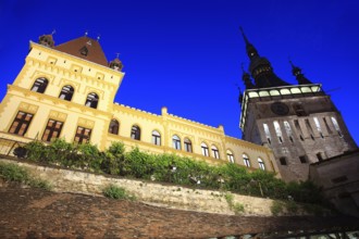 Romania, hour tower and the cultural house at the blue hour in the historic old town of Sighisoara,