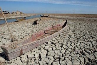 A traditional Marsh Arab canoe known as a Mashoof is left abandoned on the dry cracked earth of the