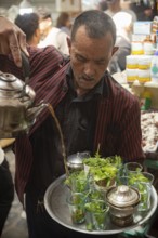 Tunis, Tunisia. 13th May 2024 A Tunisian man pours a glass of tradition mint tea in the busy