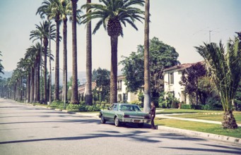 Woman standing by Chrysler Plymouth Volarét car in Beverly Hills, California, characterized by its