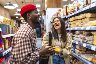 Happy young couple enjoying shopping together, smiling and talking in a store aisle while holding