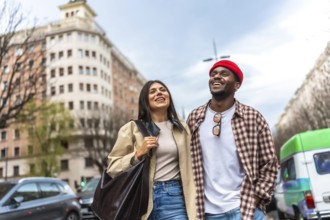 Happy multicultural couple walking together, smiling cheerfully while exploring the urban