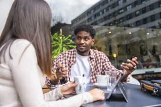 African american man and caucasian woman in lively outdoor cafe meeting, sharing ideas over coffee