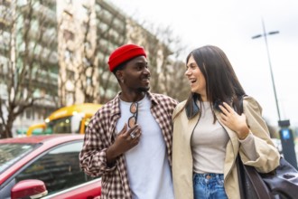 Diverse young couple walking together in an urban setting, enjoying a candid moment and sharing