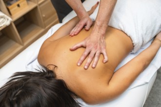 Young woman lying on spa table receiving therapeutic back massage from professional masseur, hands