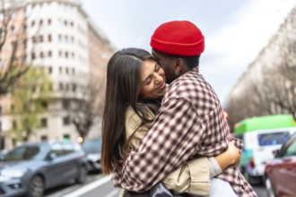 Young diverse couple embracing on an urban street, expressing love and affection, with a multi