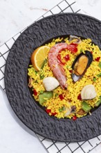 Seafood paella on a black plate, no people