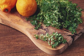 Lemon thyme, on a wooden chopping board, with lemons, close-up