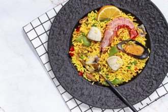 Seafood paella on a black plate, no people