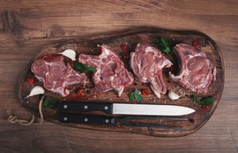 Raw calf meat, meat on the bone, meat for barbecue, cutting board, with spices and herbs, top view