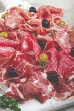 Assorted, meat appetizer, prosciutto, salami and ham, with olives, close-up, breakfast, top view,