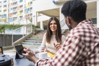 Diverse coworkers having a casual coffee break, discussing business and collaborating on a tablet