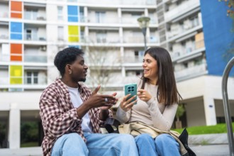 Diverse friendship bond as a young african american man and a young caucasian woman sit outdoors,