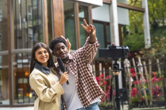 Diverse woman holding a microphone and smiling while man gestures cheerfully as they film a