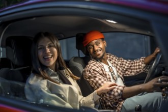 Smiling young diverse couple enjoying a pleasant car journey, with the man driving and the woman as