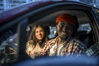 Young couple sharing a city rideshare at night, smiling in the car under street lights, enjoying an