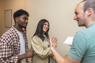 Diverse indoor group smiling, talking and listening during a casual meeting or workshop, exchanging