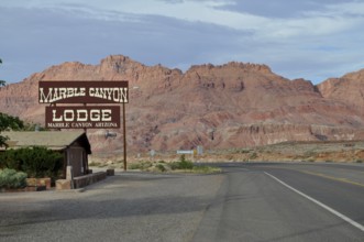 Lodge on a road in the desert in front of a rocky landscape with clouds in the sky, Grand Canyon