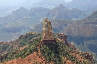 A distinctive rock formation rises in the midst of a rough and dry canyon landscape with wide