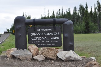 Grand Canyon National Park entrance sign surrounded by trees and stones, Grand Canyon National