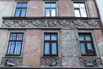 Relief band with cornucopias and figures on a dilapidated house façade from the 19th century,