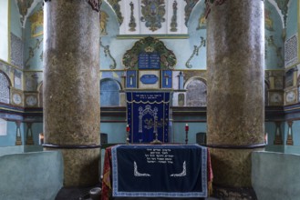 Columns of the central bima, a parish in the back, curtain in front of the Torah shrine, synagogue