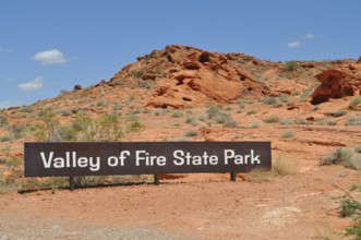 Valley of Fire State Park sign against a red rocky landscape under a blue sky, Valley of Fire State