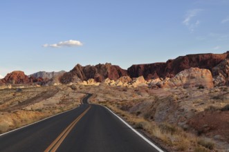Small, winding road leads through red rocky landscape in the desert at sunset, Valley of Fire State