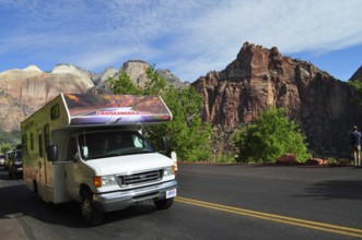 Motorhome on a road in front of impressive mountain panorama under blue sky, Zion National Park,