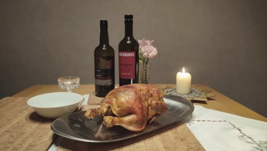 Roasted chicken on a table decorated with candlelight, wine bottles and flowers