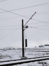 Snow-covered landscape with power pole and power lines on snow-covered railway tracks, Thuringian