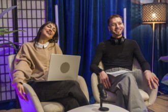 Two young diverse content creators smiling and sharing ideas during an online podcast recording