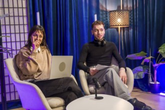 Two young content creators engaging in a podcast recording session, using a laptop, microphone, and