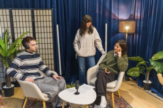 Three young people collaborating in a modern studio setup, creating audio content for a podcast or