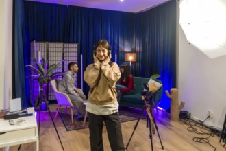 Young woman smiling and wearing headphones while standing in a trendy podcast and content creation