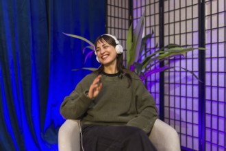 Young woman wearing headphones and smiling, actively engaging in content creation during a podcast