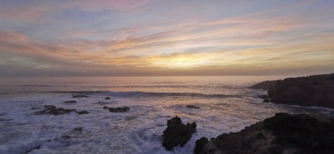 Pastel-coloured sunset over the sea. The light of the sky is reflected gently over the waves,