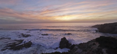 A gentle sunset with pastel-colored sky over the roaring sea, hiking the Fisherman's Trail,