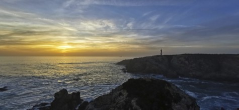 A coastal scene with a lighthouse at sunset. The clouds color the sky colorful, hiking on the