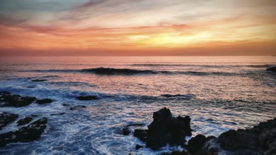 Impressive sunset with orange sky and dark rocks by the sea, hiking on the Fisherman's Trail,