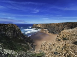 Extensive coastal view with dramatic cliffs and deep blue ocean under a clear sky, hiking on the