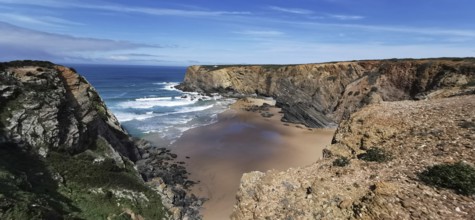 Wide sandy bay surrounded by rugged cliffs with gentle waves, hiking on the Fisherman's Trail,